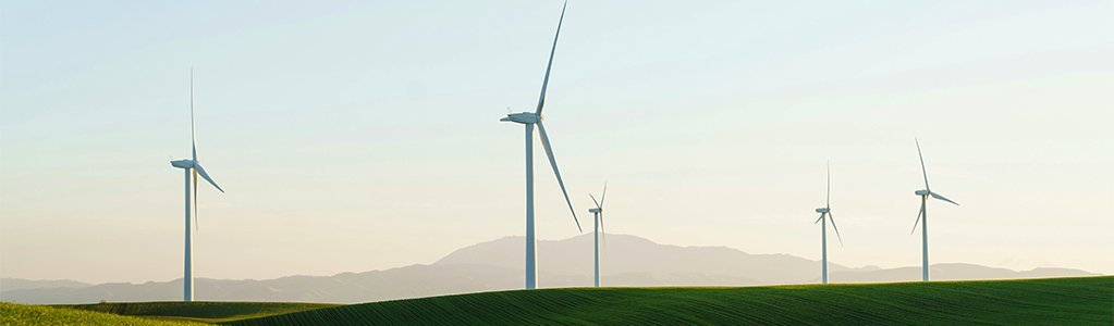 a green field stretches out with several wind turbines visible in the distance