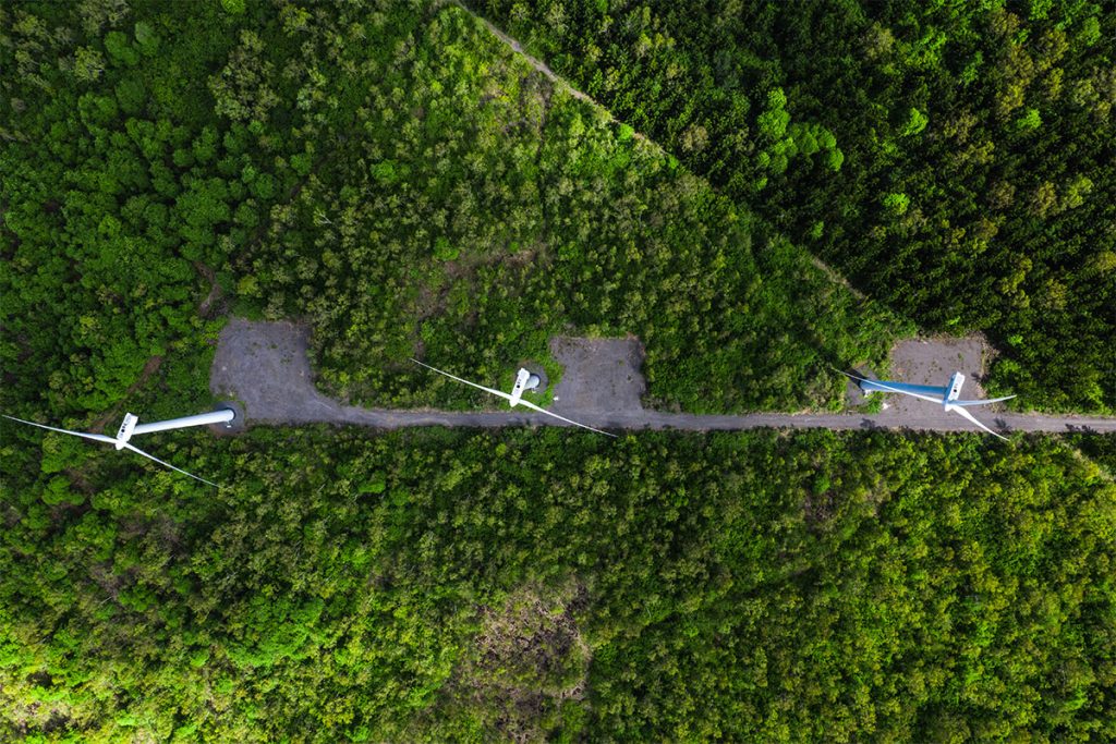 aerial view of three wind turbines among lush green field