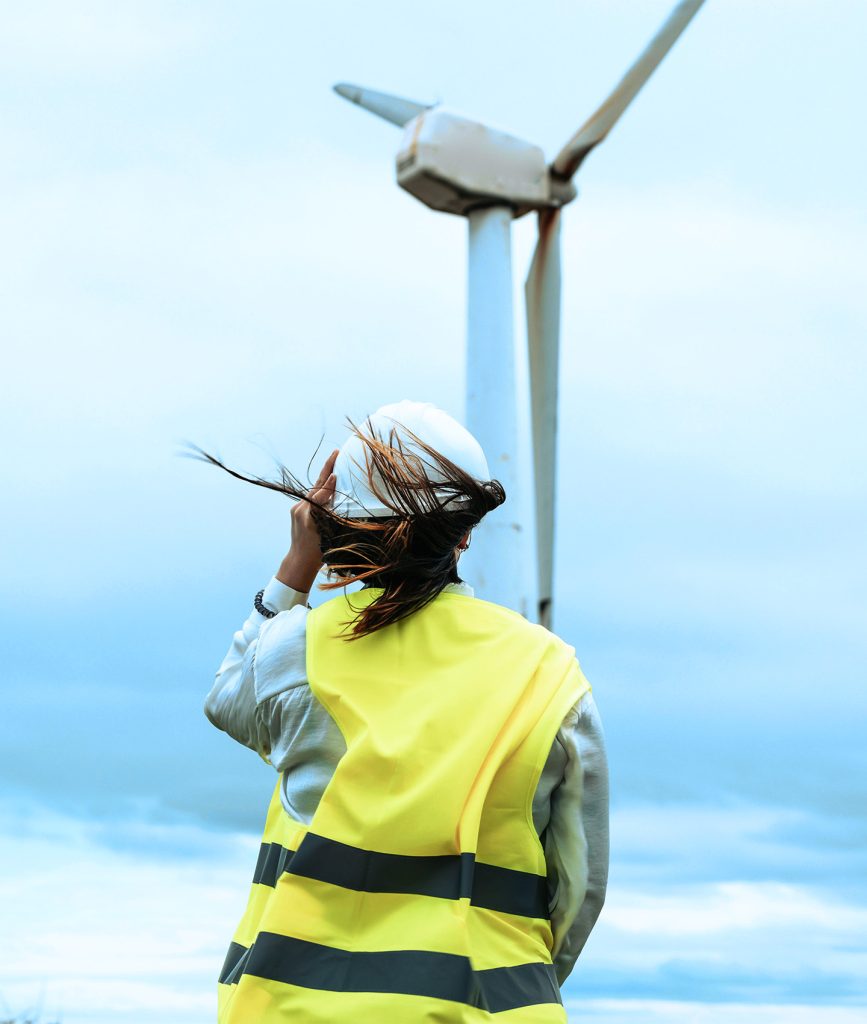 woman engineer standing in front of a wind turbine