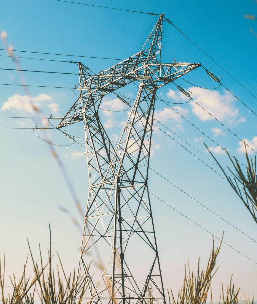low angle view of pylon and overhead high voltage power lines