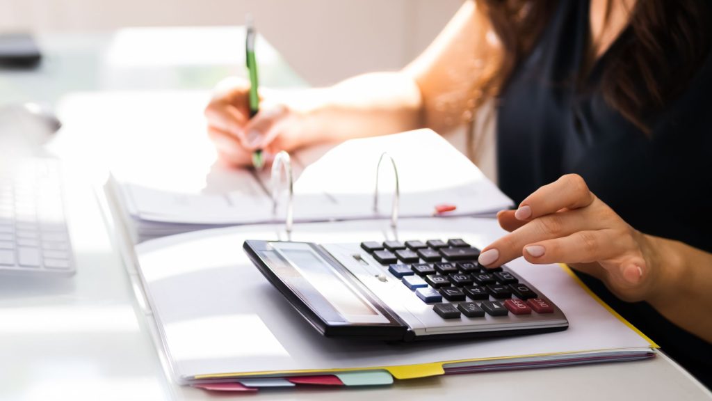 Woman using a calculator to compute tax burdens when inheriting a solar or wind farm