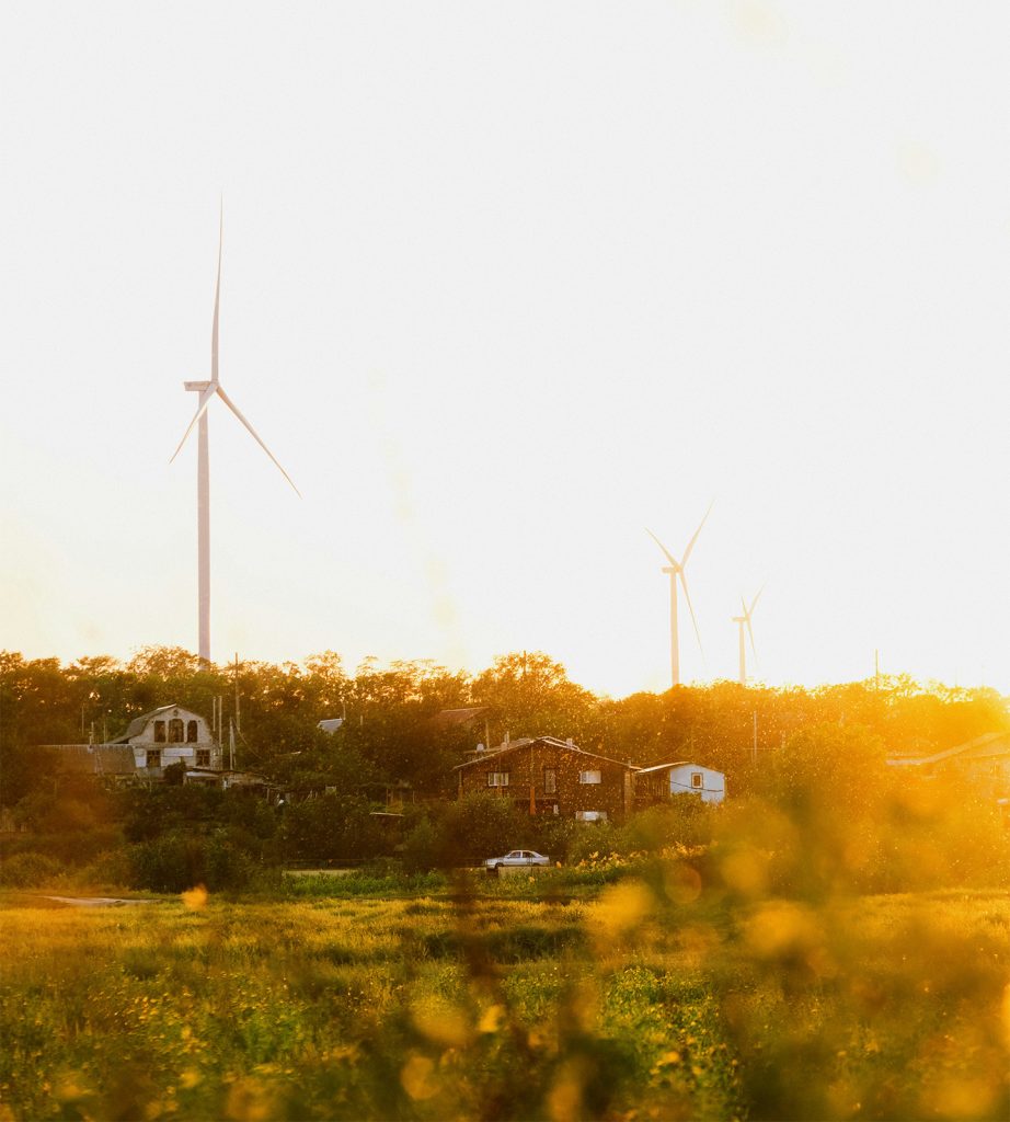 wind turbines behind residential houses during sunset